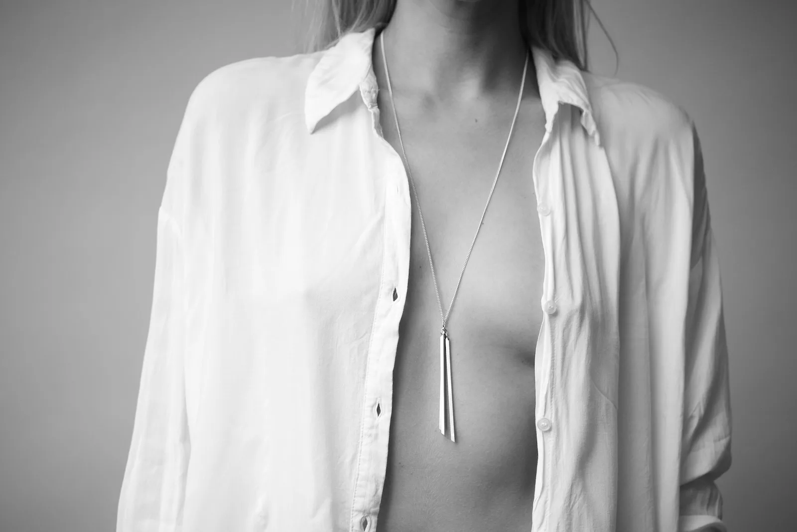 Chest and neckline with a silver pendant necklace over a white shirt