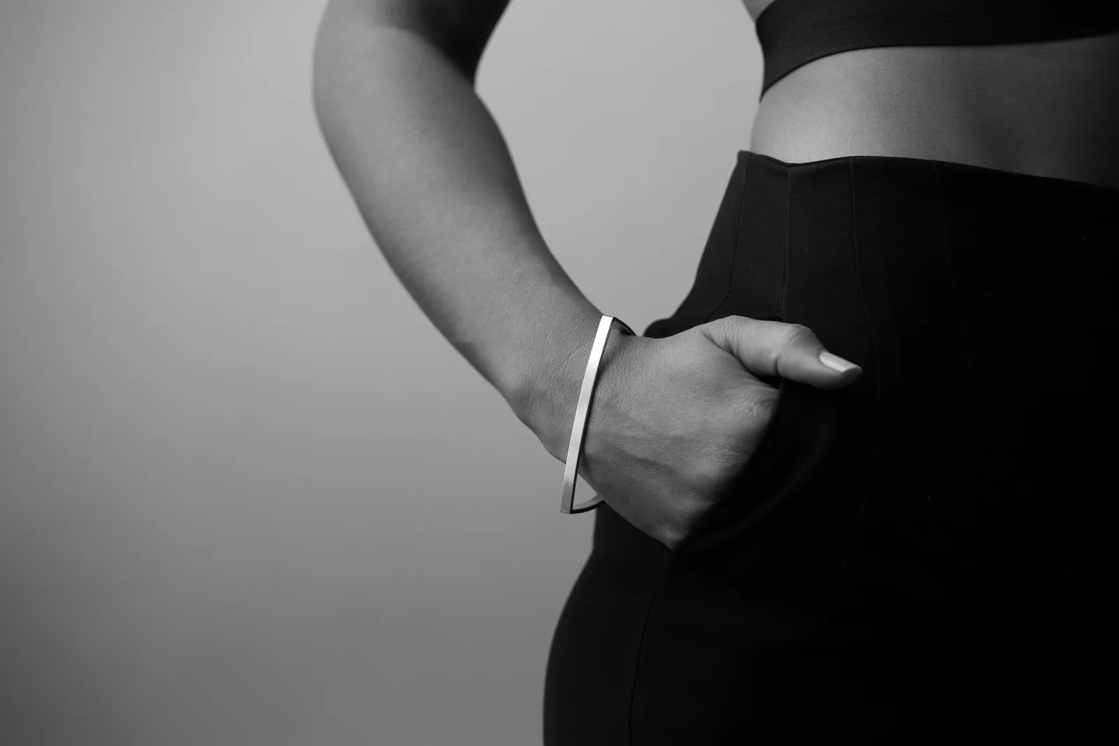 Torso with a single thin silver bracelet, hand in pocket