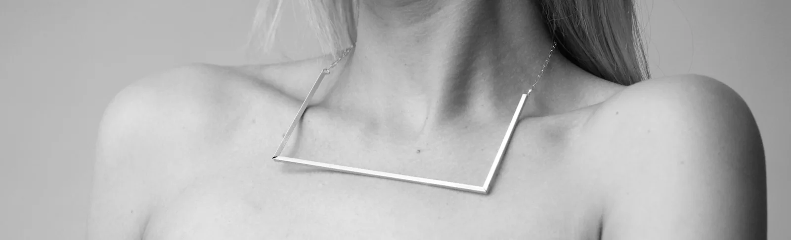 Silver angular necklace on a person, neck and shoulders shown