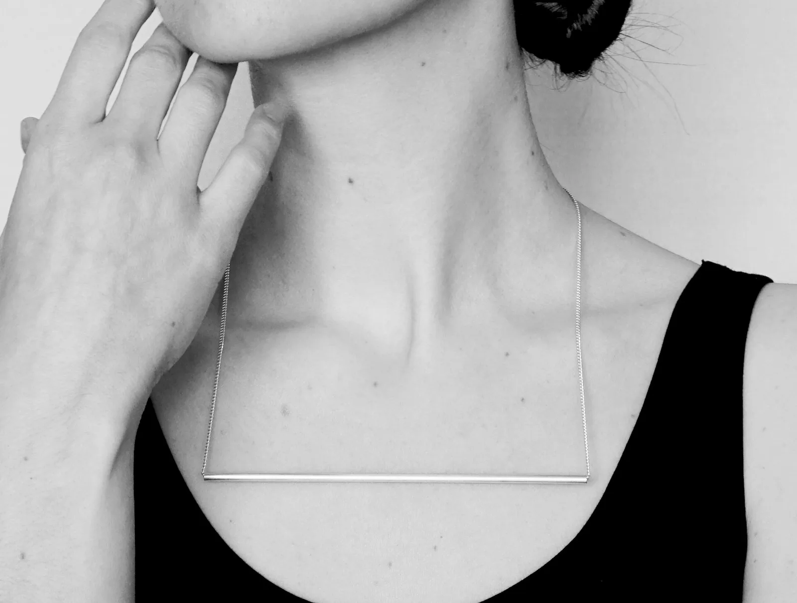 Portrait of a woman wearing a silver necklace with a wide straight tube form