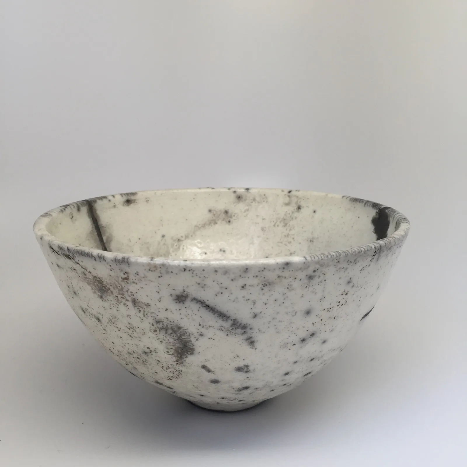 Ceramic bowl made using the Japanese raku firing technique, with characteristic uneven surface texture