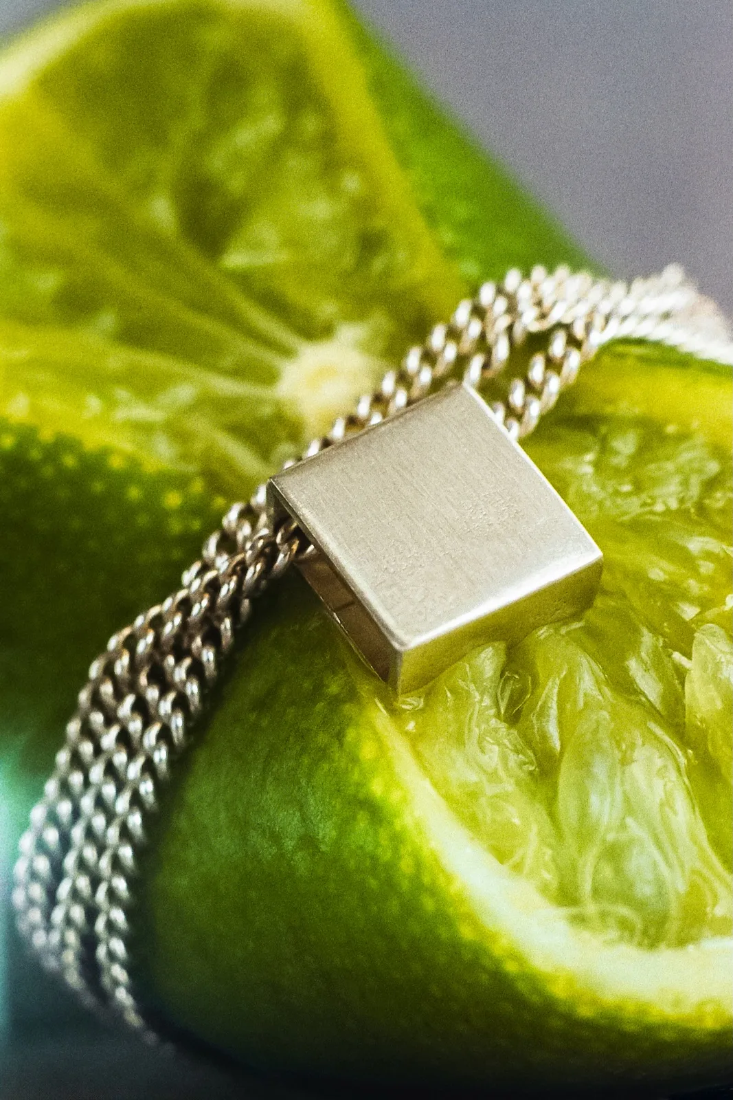 Silver chain necklace tightly wrapped around a halved green lime