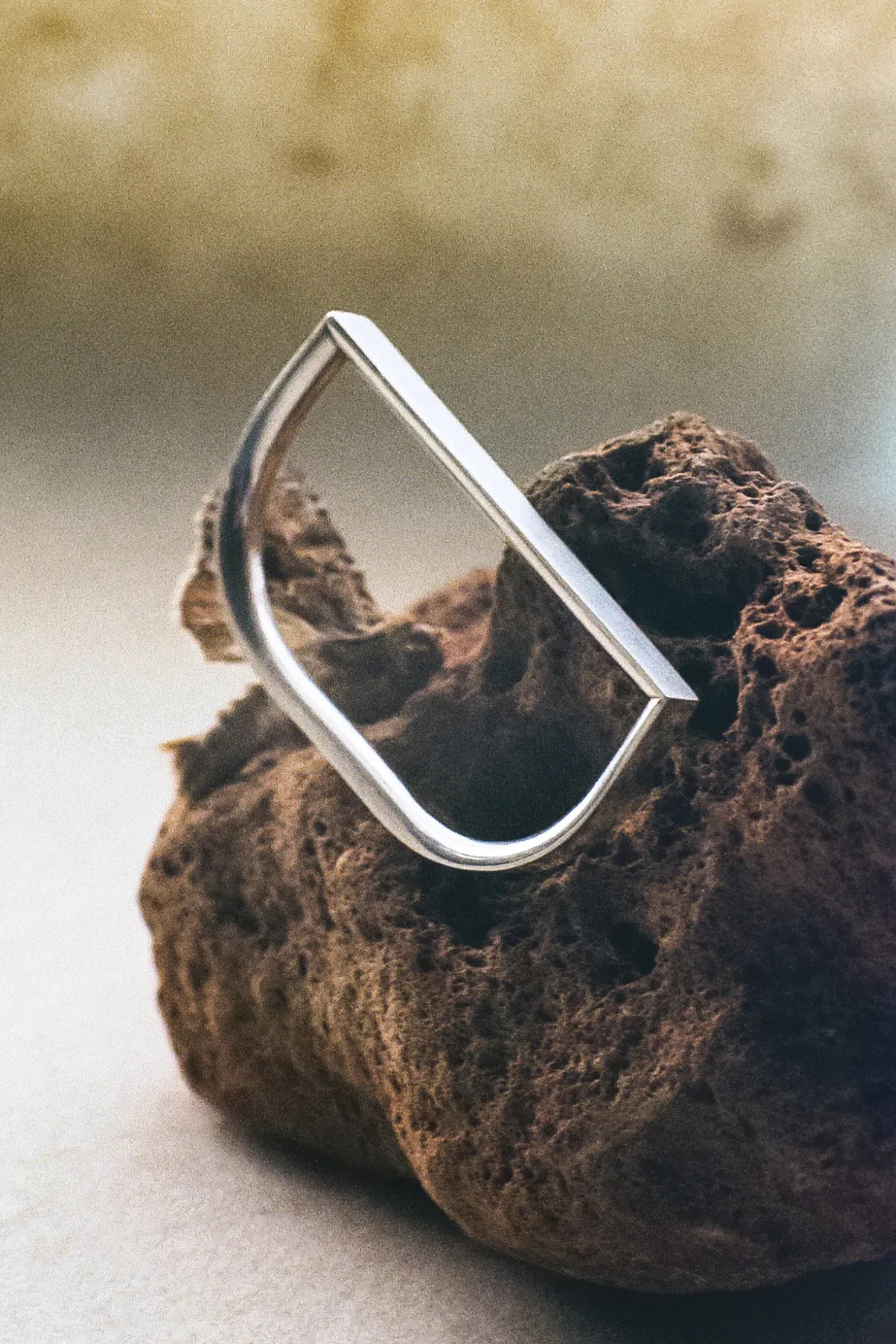 Silver rectangular ring resting on a dark rough stone
