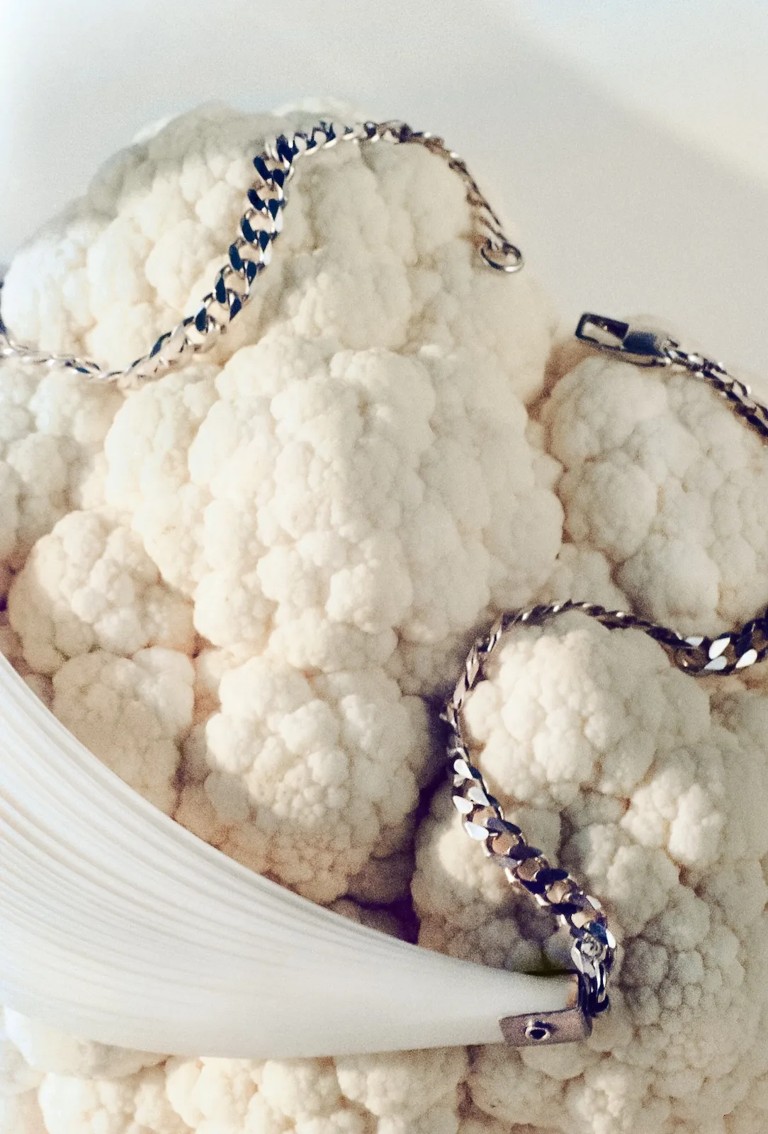 White Mylar and sterling silver necklace draped over a white cauliflower
