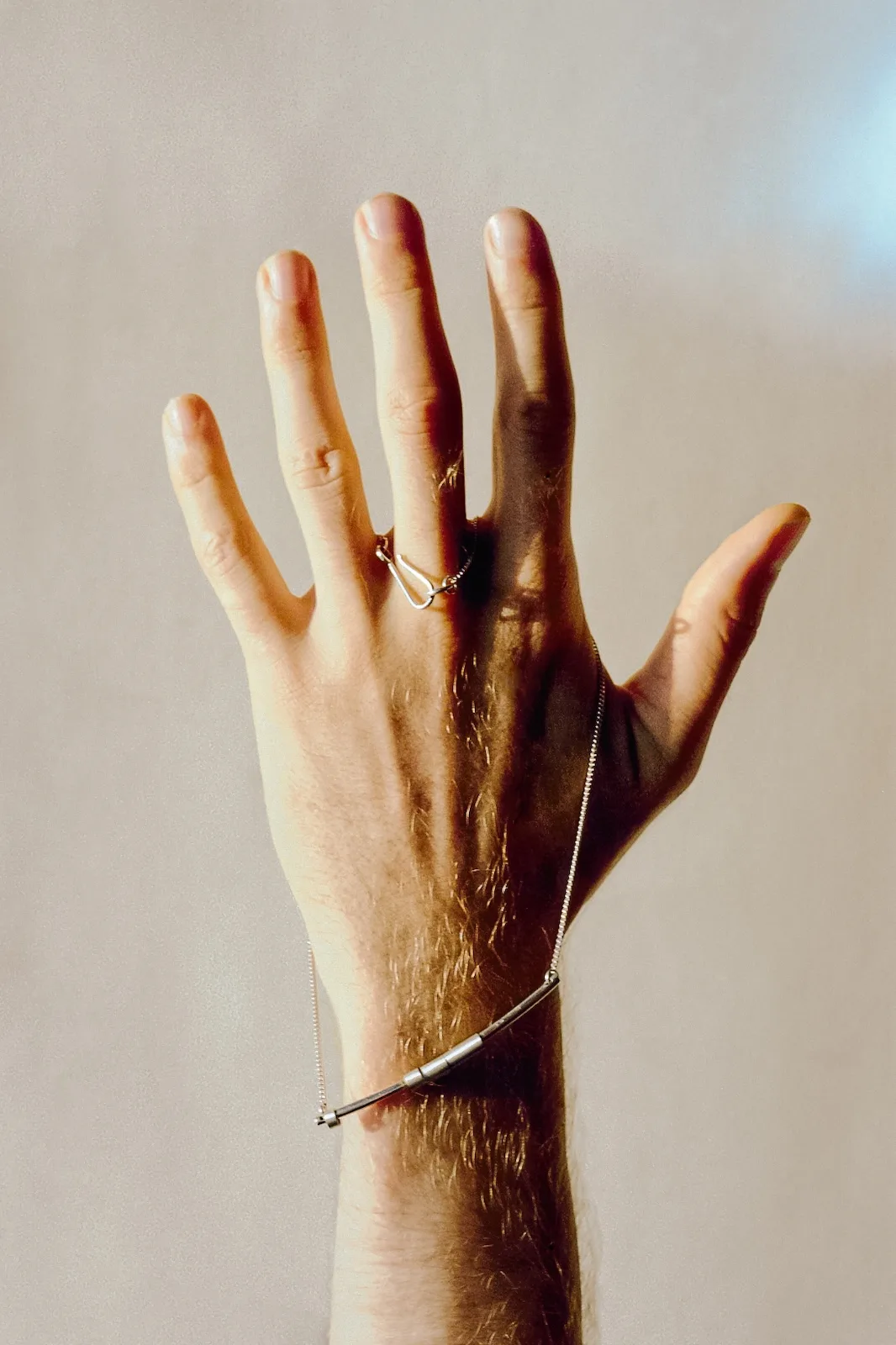 Hand with a silver necklace draped over it