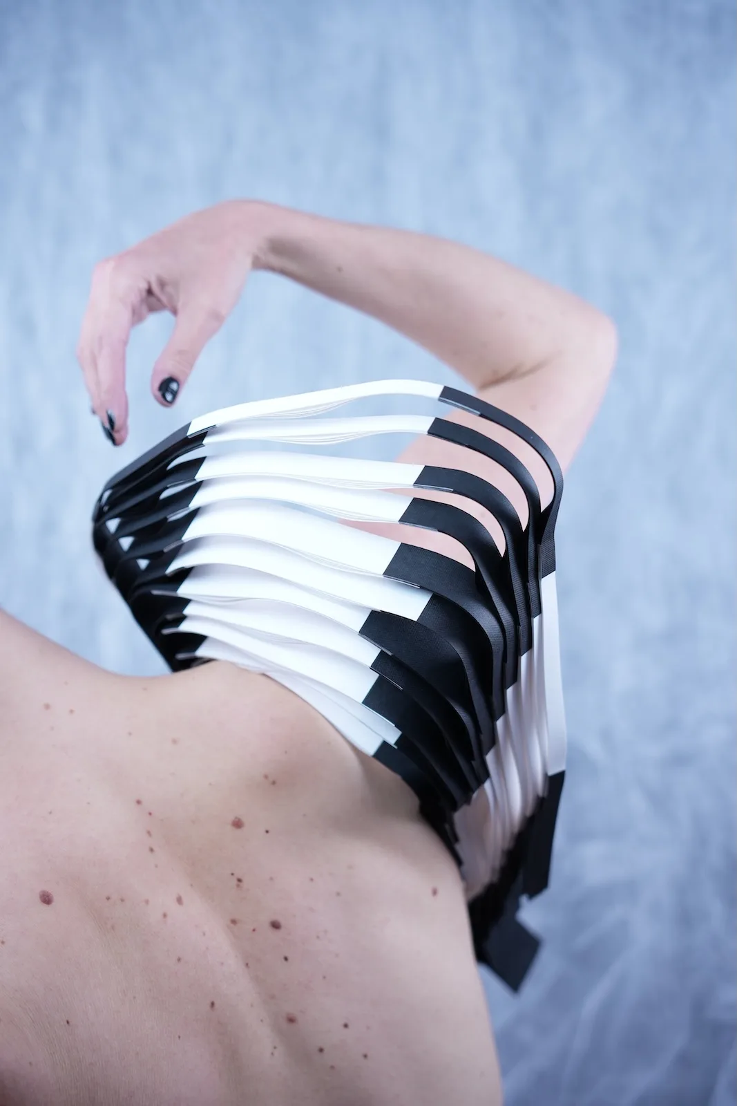 Close-up of torso wearing a structured black and white paper wearable art piece with stacked geometric panels
