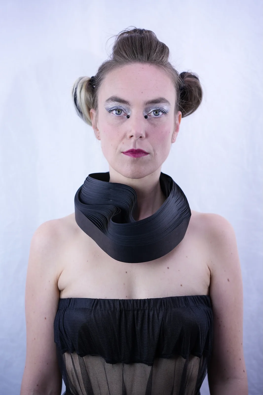 Model wearing a large circular black paper collar, front-facing