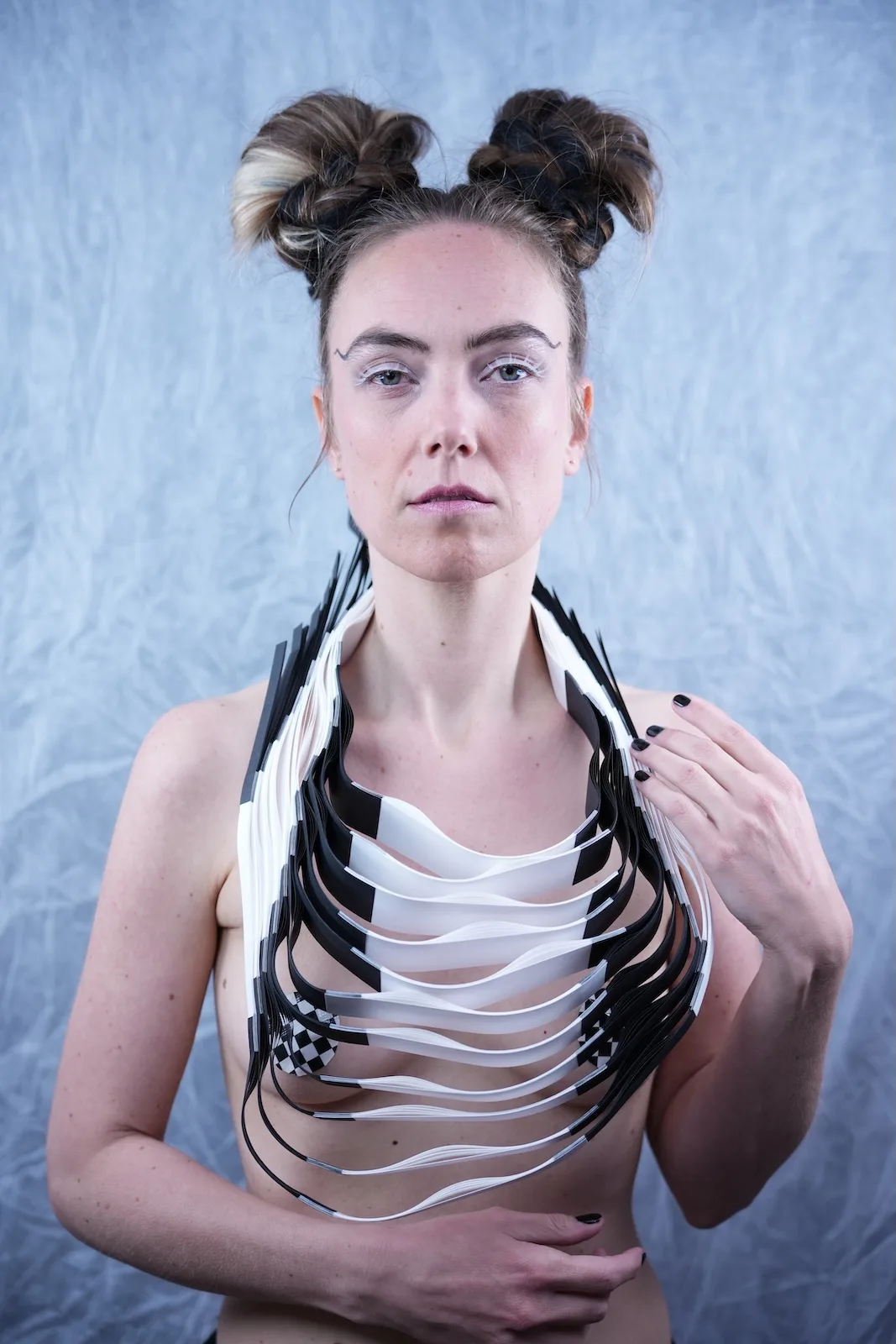 Portrait of model wearing a layered sculptural paper neckpiece in black and white